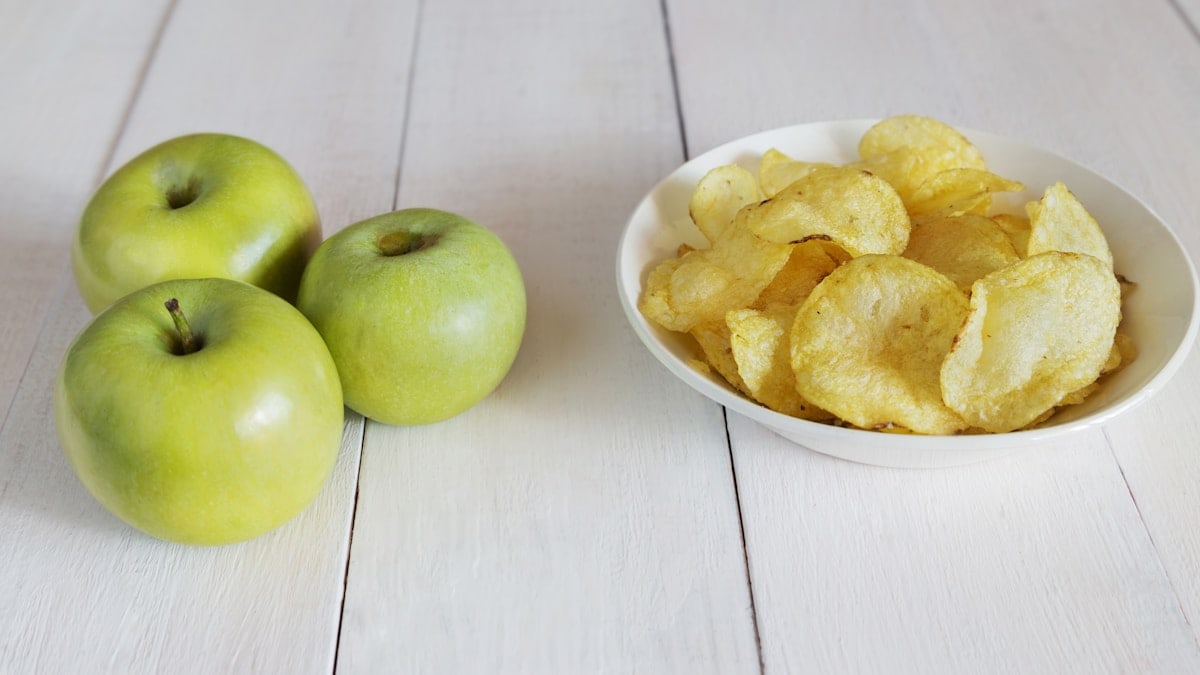 Green apples and a bowl of potato chips